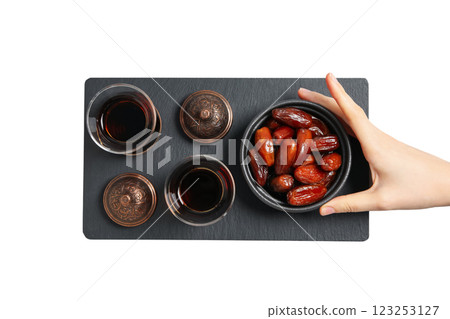 Dried dates in a bowl, black tea in Arbudu glasses, bronze bowl on a black plate and hand, top view, isolated on white background, PNG Dried dates in a bowl, black tea in Arbudu glasses, bronze bowl on a black plate and hand, top view, isolated on white background, PNG 123253127
