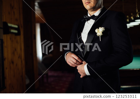 Groom in white shirt, suit and bow tie holding lapel of his jacket indoors. Wedding concept. Groom in white shirt, suit and bow tie holding lapel of his jacket indoors. Wedding concept. 123253311