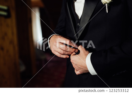 Groom in white shirt, suit and bow tie holding lapel of his jacket indoors. Wedding concept. Groom in white shirt, suit and bow tie holding lapel of his jacket indoors. Wedding concept. 123253312