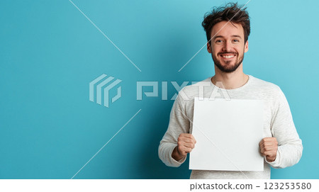 Happy man showing a blank white board against a blue background. He has a scruffy beard and messy hair and a big smile on his face. Happy man showing a blank white board against a blue background. He has a scruffy beard and messy hair and a big smile on his face. 123253580