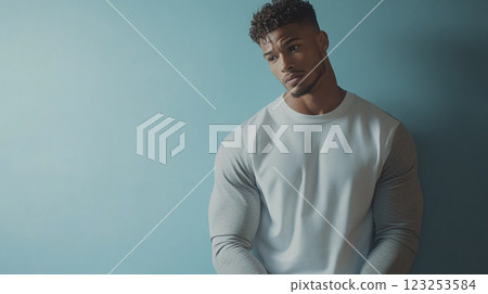 Portrait of a stylish man with a contemplative gaze. He is wearing a two-tone shirt against a solid blue background, emphasizing his physique. 123253584
