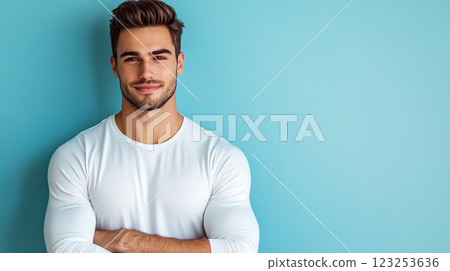 Confident man smiles with arms crossed in a white long-sleeved shirt, against a plain light blue background, exuding health and positivity. Confident man smiles with arms crossed in a white long-sleeved shirt, against a plain light blue background, exuding health and positivity. 123253636