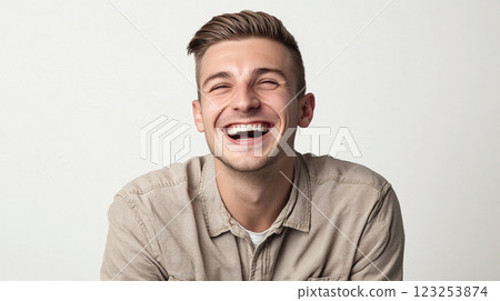 Man with a bright smile and well-groomed hair. His laughter is infectious as he beams at the camera against a neutral backdrop. Man with a bright smile and well-groomed hair. His laughter is infectious as he beams at the camera against a neutral backdrop. 123253874