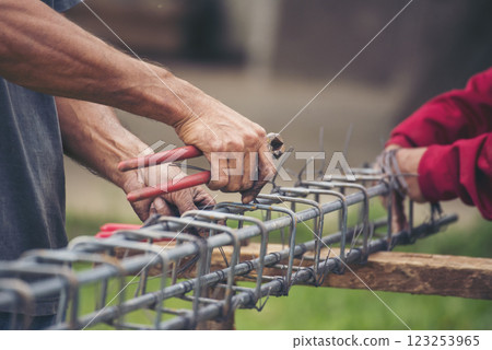 Construction Worker hands using pincer pliers iron wire. Outdoor Worker using wire bending pliers, construction work. Men hands bending cutting steel wire fences bar reinforcement of concrete work 123253965