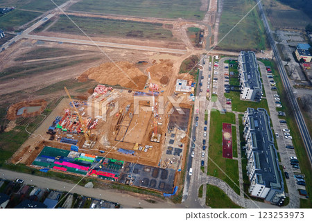 Aerial view of residential buildings under construction surrounded by completed homes and apartments. Cranes, foundations and building materials at construction site. New neighborhood in small town Aerial view of residential buildings under construction surrounded by completed homes and apartments. Cranes, foundations and building materials at construction site. New neighborhood in small town 123253973