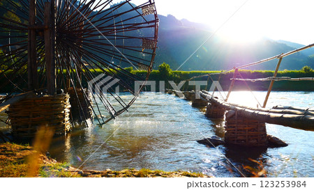 Wood water wheel Baler Machine in Agriculture Farm impeller lifted pumping water in river. Wooden Water Baler Machine green garden Farm blades by windy natural. Sustainable Resources Environment 123253984