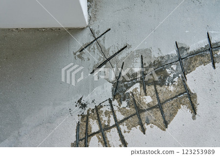 Close-up of concrete surface under repair with reinforcement bars inserted into cracks. Repairing cracks in concrete floor. Building renovation process 123253989