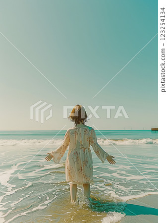 Carefree woman in floral dress stepping into the sea 123254134