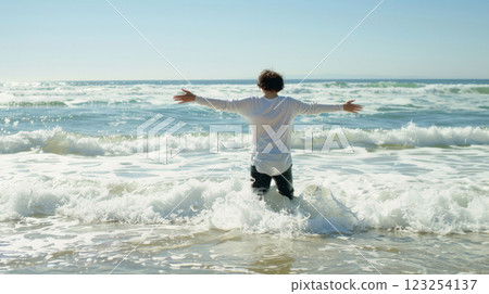 Man with open arms standing in ocean waves 123254137