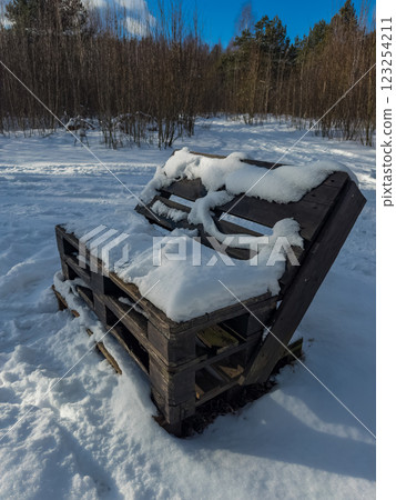 Snow-covered wooden pallet bench in a winter landscape, forest backdrop. High quality photo Snow-covered wooden pallet bench in a winter landscape, forest backdrop. High quality photo 123254211