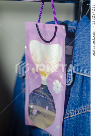 Purple hanging moisture absorber bag collecting humidity in a closet space. High quality photo 123254213