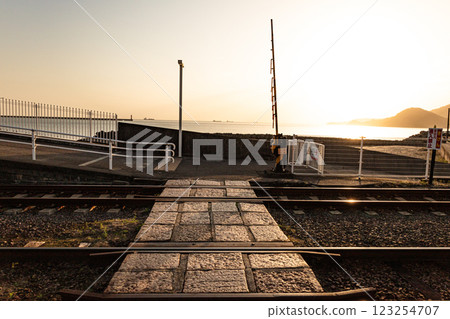 A view of a railway crossing with a view of the sea lit by the afterglow of dusk, evoking a youthful atmosphere A view of a railway crossing with a view of the sea lit by the afterglow of dusk, evoking a youthful atmosphere 123254707