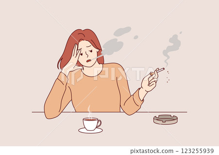 Woman smokes cigarette and drinks hot coffee, sitting at table taking break after difficult work Woman smokes cigarette and drinks hot coffee, sitting at table taking break after difficult work 123255939