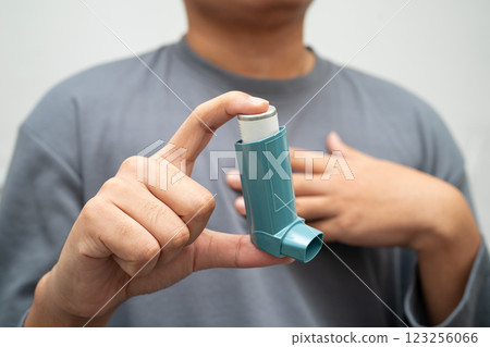 Asthma and chronic obstructive pulmonary disease COPD, Asian young man using metered dose inhaler MDI. Asthma and chronic obstructive pulmonary disease COPD, Asian young man using metered dose inhaler MDI. 123256066