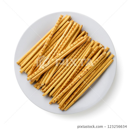 Pile of pretzel sticks on a plate close-up on a white background. Top view 123256634