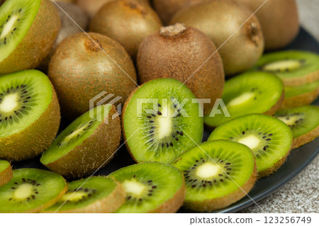Plate of sliced and whole fresh kiwi fruit. 123256749