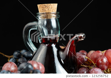 Red wine vinegar in glass vinegar bowl cruet among grapes 123256752
