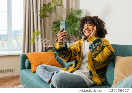 African American girl holding smartphone having video chat. Female blogger chatting with best friends in social network. Young woman having virtual meeting online chat video call at home African American girl holding smartphone having video chat. Female blogger chatting with best friends in social network. Young woman having virtual meeting online chat video call at home 123256957