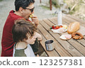 Close-up view of father and his school boy son on a family picnic in the mountains. Child kid and his dad taking a rest and enjoying a picnic while hiking in the mountains 123257381