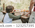 Close-up view of father and his school boy son on a family picnic in the mountains. Child kid and his dad taking a rest and enjoying a picnic while hiking in the mountains 123257395