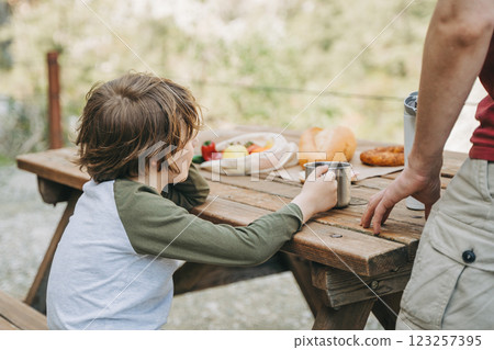 Close-up view of father and his school boy son on a family picnic in the mountains. Child kid and his dad taking a rest and enjoying a picnic while hiking in the mountains Close-up view of father and his school boy son on a family picnic in the mountains. Child kid and his dad taking a rest and enjoying a picnic while hiking in the mountains 123257395
