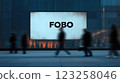 A large advertising screen displays the word 'FOBO' prominently. Silhouetted pedestrians walk by in a modern urban setting. The background features buildings and a subtle glow. 123258046