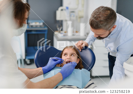 Cute girl during annual dental check-up in dental clinic, father supporting her. 123258219