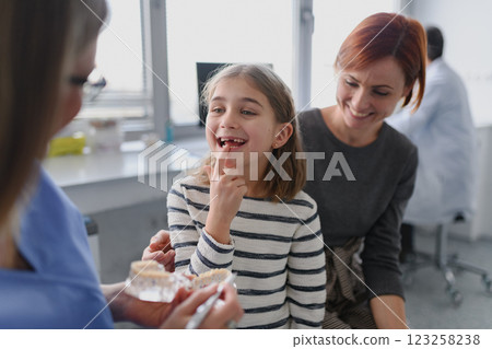 Girl showing her lost tooth to the dentist during a routine checkup at the dental clinic. Girl showing her lost tooth to the dentist during a routine checkup at the dental clinic. 123258238