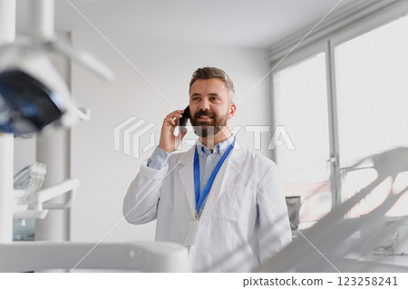 Portrait of handsome doctor in doctors office make phone call with patient. 123258241