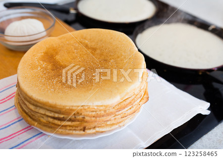 Freshly baked hot cereal pancakes on plate and pans during cooking 123258465