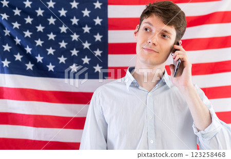 Satisfied student talking on mobile phone against background of USA flag 123258468