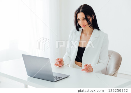 Brunette Woman In White Business Suit With Laptop Online In Office At Training Brunette Woman In White Business Suit With Laptop Online In Office At Training 123259552