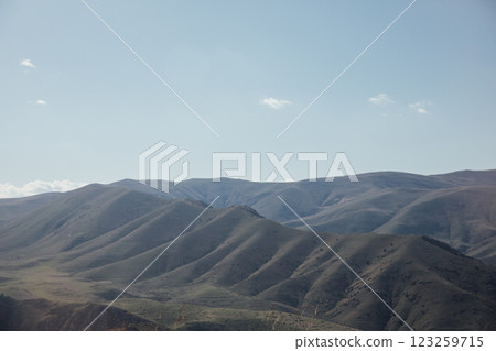 A beautiful landscape of snow-capped mountains and green meadows and a sky with clouds 123259715