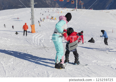Female instructor teaches child to snowboard in ski resort Female instructor teaches child to snowboard in ski resort 123259725