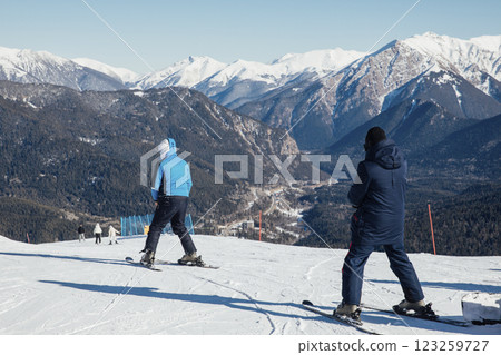 Skiers and snowboarders skiing on a snowy slope at a ski resort 123259727
