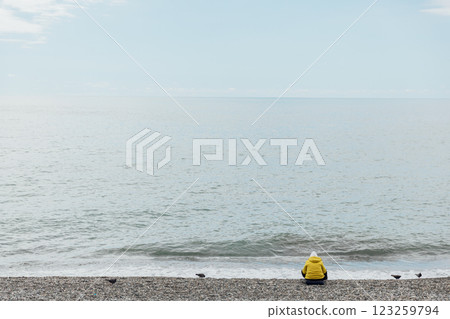 One person sitting on the beach and looking at the sea One person sitting on the beach and looking at the sea 123259794