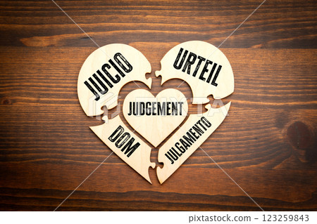 JUGEMENT. Spanish, Polish, Portuguese, Swedish. Wooden puzzle in the shape of a heart on a wooden 123259843