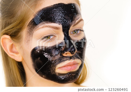 Woman applying black cleanser mask to face 123260491