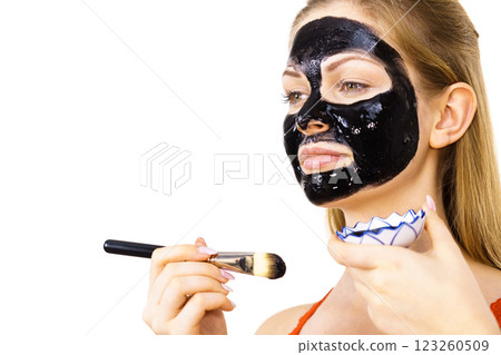 Woman applying black mud mask to face Woman applying black mud mask to face 123260509