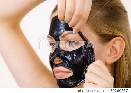 Girl removes black mask from face 123260587