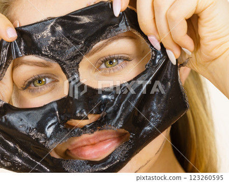 Girl removes black mask from face Girl removes black mask from face 123260595