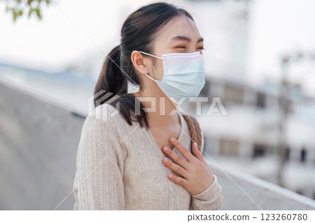 Cheerful woman in a mask smiling while using her smartphone, promoting health and safety in polluted areas. 123260780