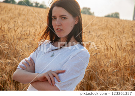 Young woman standing in wheat field at sunset for rural lifestyle concept. Harvesting concept Young woman standing in wheat field at sunset for rural lifestyle concept. Harvesting concept 123261337