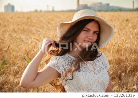Young woman in sun hat enjoying a wheat field at sunset. Harvesting concept Young woman in sun hat enjoying a wheat field at sunset. Harvesting concept 123261339