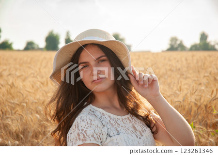 Young woman in wheat field with sun hat on a sunny day. Harvesting concept Young woman in wheat field with sun hat on a sunny day. Harvesting concept 123261346