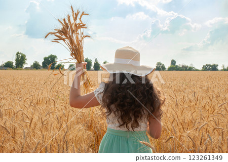 Woman enjoying summer day in wheat field holding wheat ears celebrating nature and harvesting. Harvesting concept 123261349