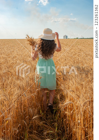Woman walking through wheat field in summer for rural escape and tranquil retreat. Harvesting concept 123261362
