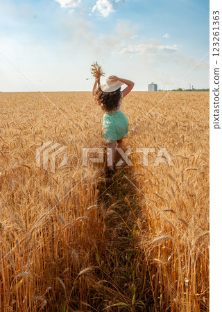 Woman walking through wheat field on a sunny day. Harvesting concept 123261363