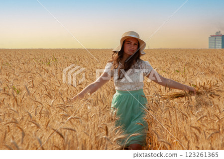 Woman in summer dress walking through wheat field. Harvesting concept 123261365