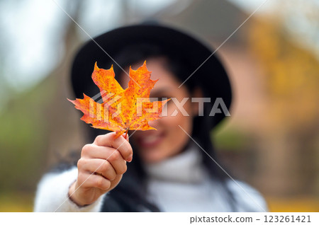 Portrait of a beautiful young woman in the autumn park with maple leaf 123261421